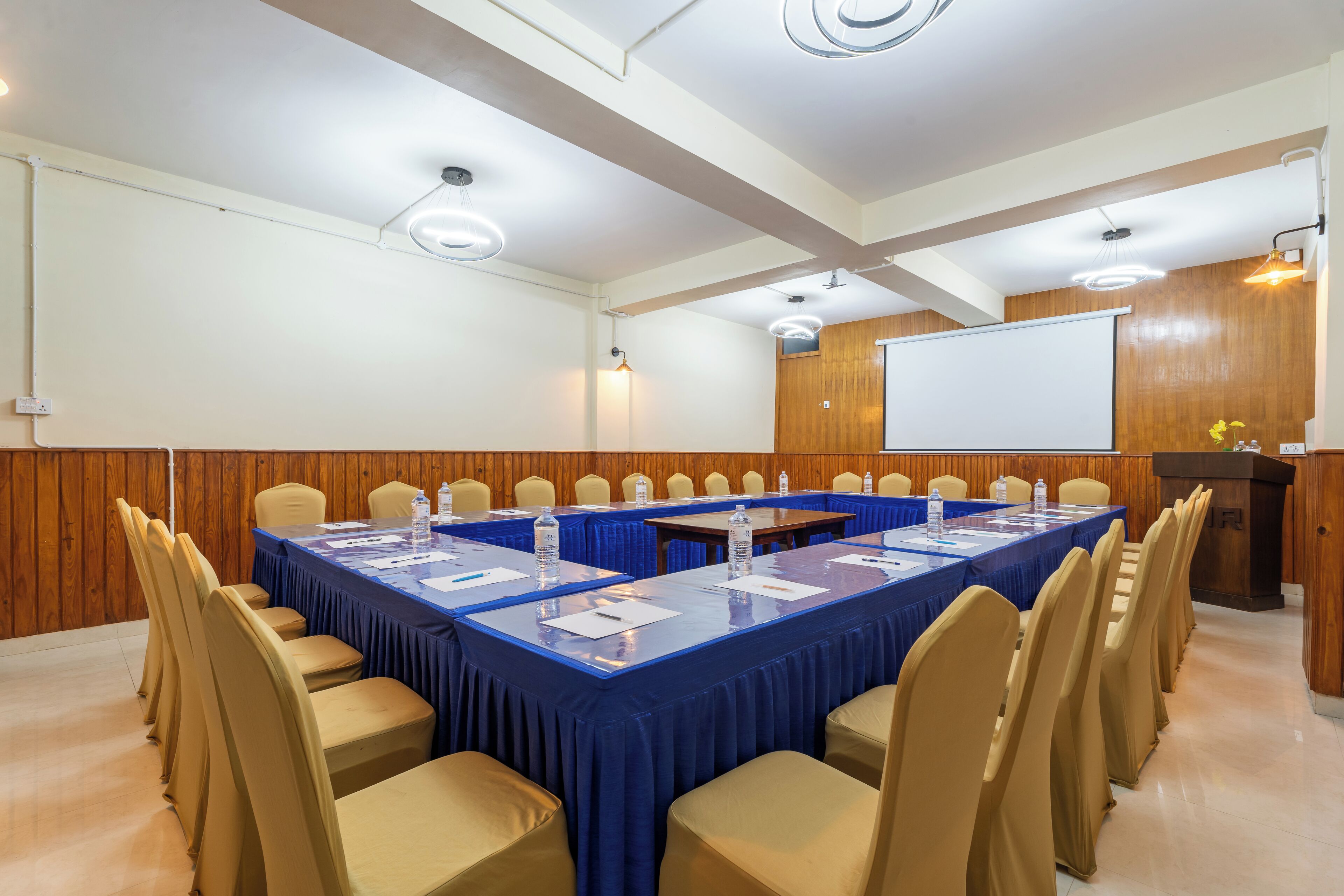A conference room with a long table, chairs, a podium, and a whiteboard.