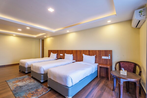 A hotel room with two beds, a desk, a chair, and a small table. - Village Highland Resort (Suryabinayak)