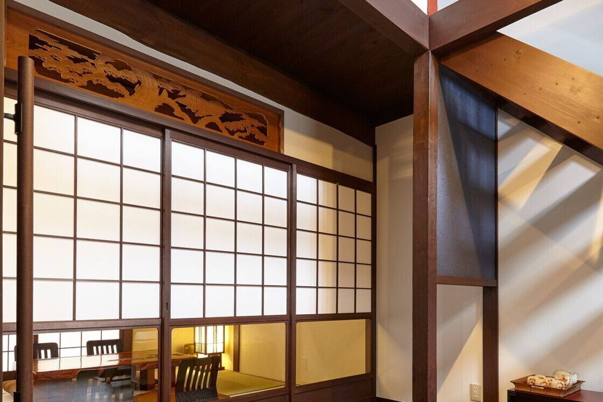 Um quarto japonês tradicional com chão de tatame, um painel de correr shoji e um banco de madeira baixo.