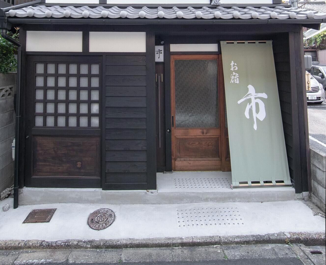 Ein traditionelles japanisches Gebäude mit Holztür, Schiebetür aus Glas und einem Schild mit japanischen Schriftzeichen.
