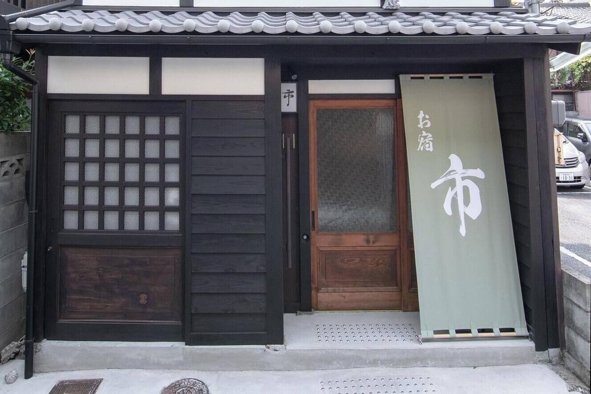 Um edifício tradicional japonês com porta de madeira, porta de correr de vidro e um letreiro com caracteres japoneses.