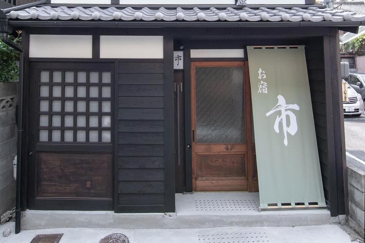 Un bâtiment traditionnel japonais doté d’une porte en bois, d’une porte coulissante en verre et d’une enseigne avec des caractères japonais.