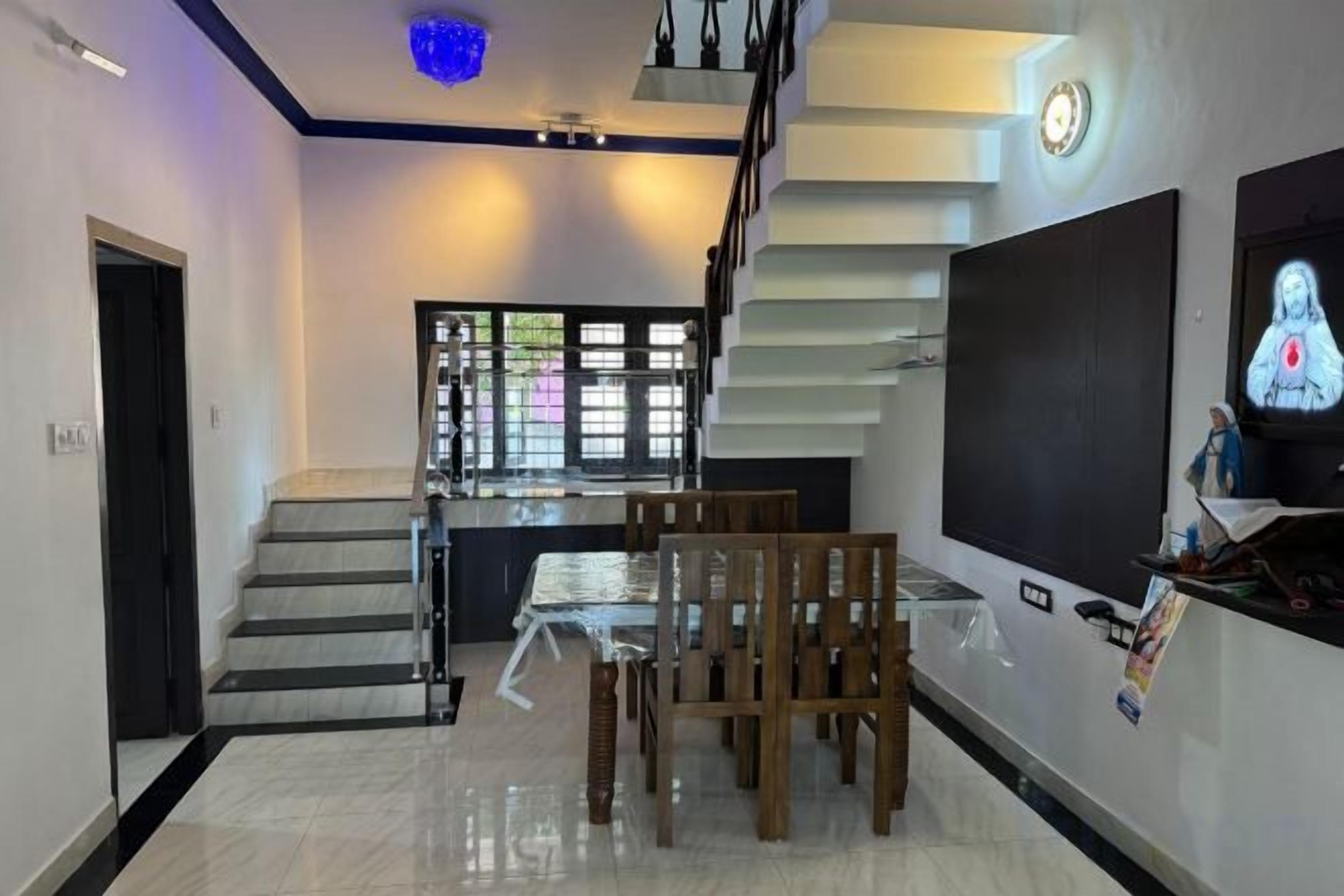 A modern interior with a staircase, dining area, and a flat-screen TV.