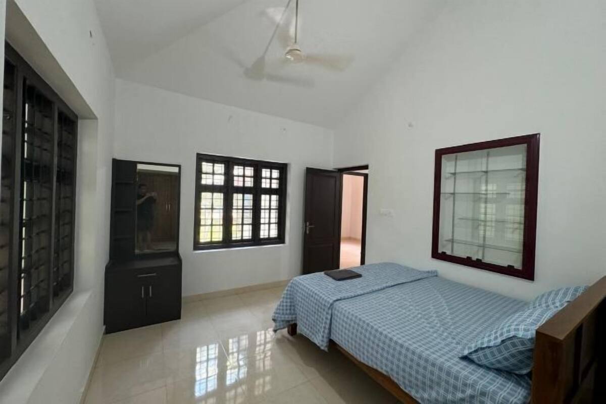 A bedroom with a bed, a wardrobe, a window, and a door.