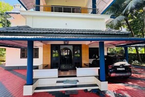 Un bâtiment à deux étages, doté d’une entrée couverte et d’une voiture garée à l’extérieur.