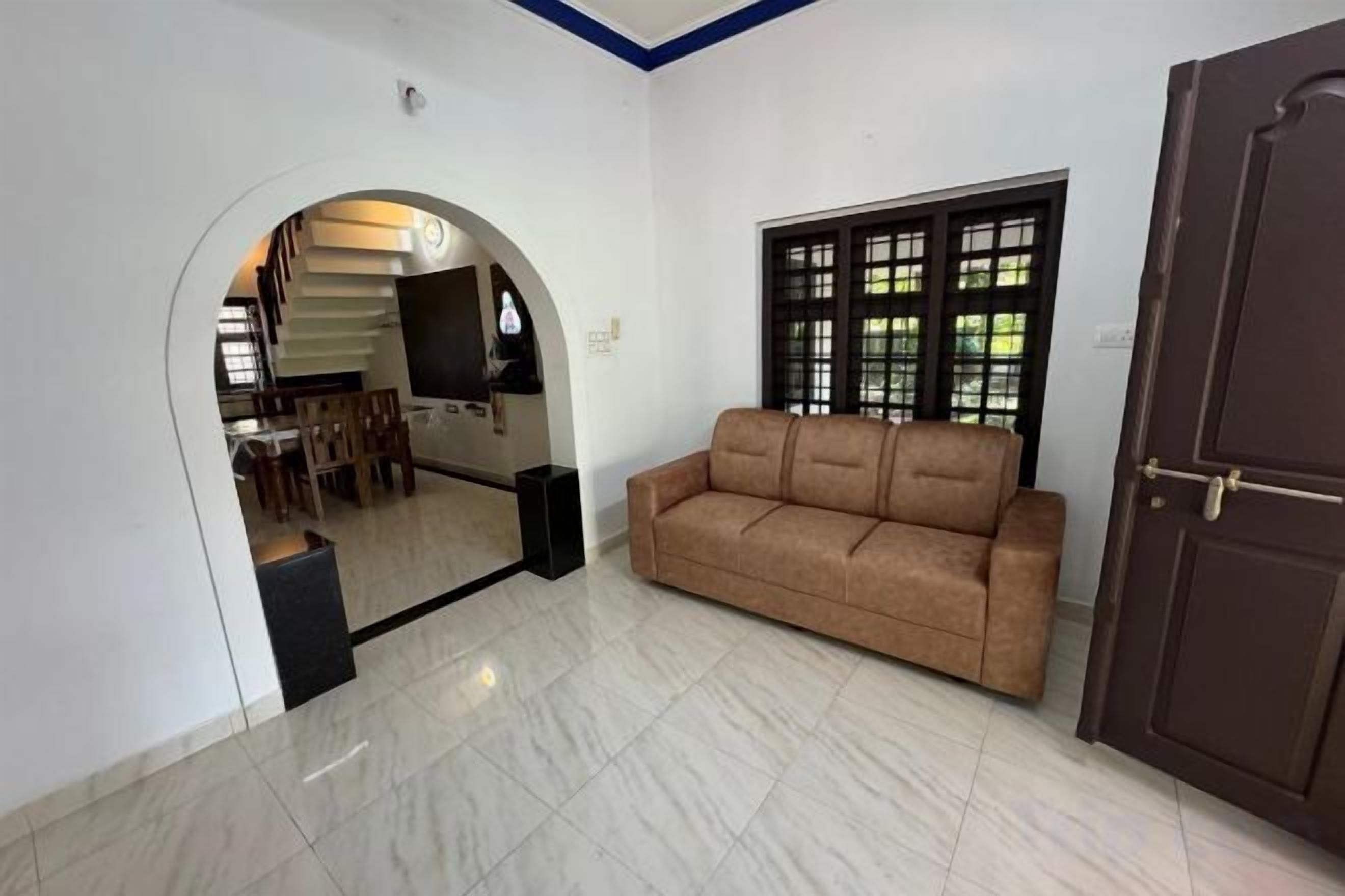 A living room with a sofa, a door, and a window with blinds.