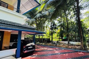 A residential property with a covered carport, a paved driveway, and a lush green garden with palm trees. - Dream House Near Iim Kozhikode & Nit Calicut (Kozhikode)