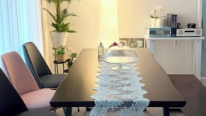 A dining table with a lace table runner, chairs, a potted plant, a lamp, and a shelf with books and a radio. - Hongik University Station 8min/Bedroom 3/Bed 4/Parking Available [Vanilla House] (Seoul)