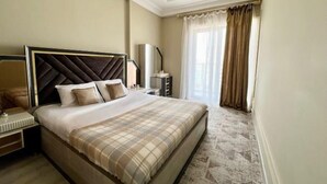 A hotel room with a large bed, a nightstand, a lamp, and a view of the outdoors through the window. - Apartments in Tashkent City 2 (Tashkent)