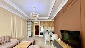 A modern living room with a sofa, a coffee table, a TV, and a dining area with chairs. - Apartments in Tashkent City 2 (Tashkent)