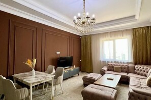 A living room with a television, sofa, coffee table, and a dining area with chairs and a table.