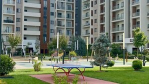 A modern apartment building with multiple balconies, a central courtyard with a ping pong table, and surrounding greenery. - Apartments in Tashkent City 2 (Tashkent)