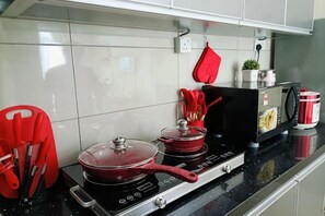 A kitchen with a stove, pots, a red oven mitt, and a coffee maker. - IOICityMall #Muji#Tatami#Babycot (Serdang)