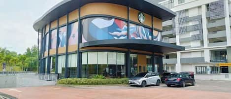 Un edificio con fachada curva, amplias ventanas y un estacionamiento con automóviles.