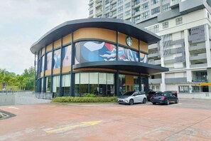 A building with a curved facade, large windows, and a parking area with cars. - IOICityMall #Muji#Tatami#Babycot (Serdang)