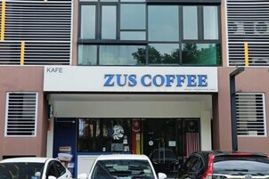 Un edificio con un letrero que dice 'ZUS COFFEE' y una entrada visible.