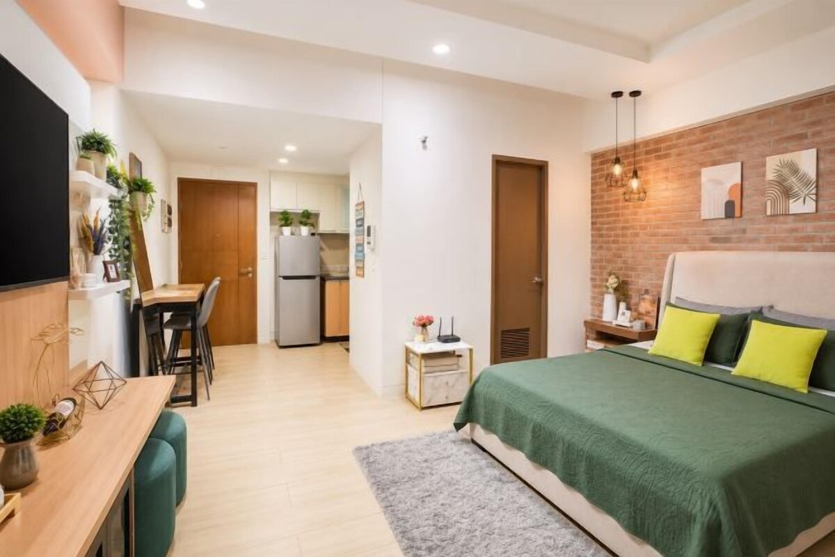 A compact living space with a bed, a desk, a chair, and a kitchenette.