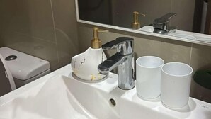 A bathroom with a white sink, a mirror, and a hand soap dispenser. - Lovely Unit with free wifi & netflix I across Naia Terminal 3 airport (Pasay)