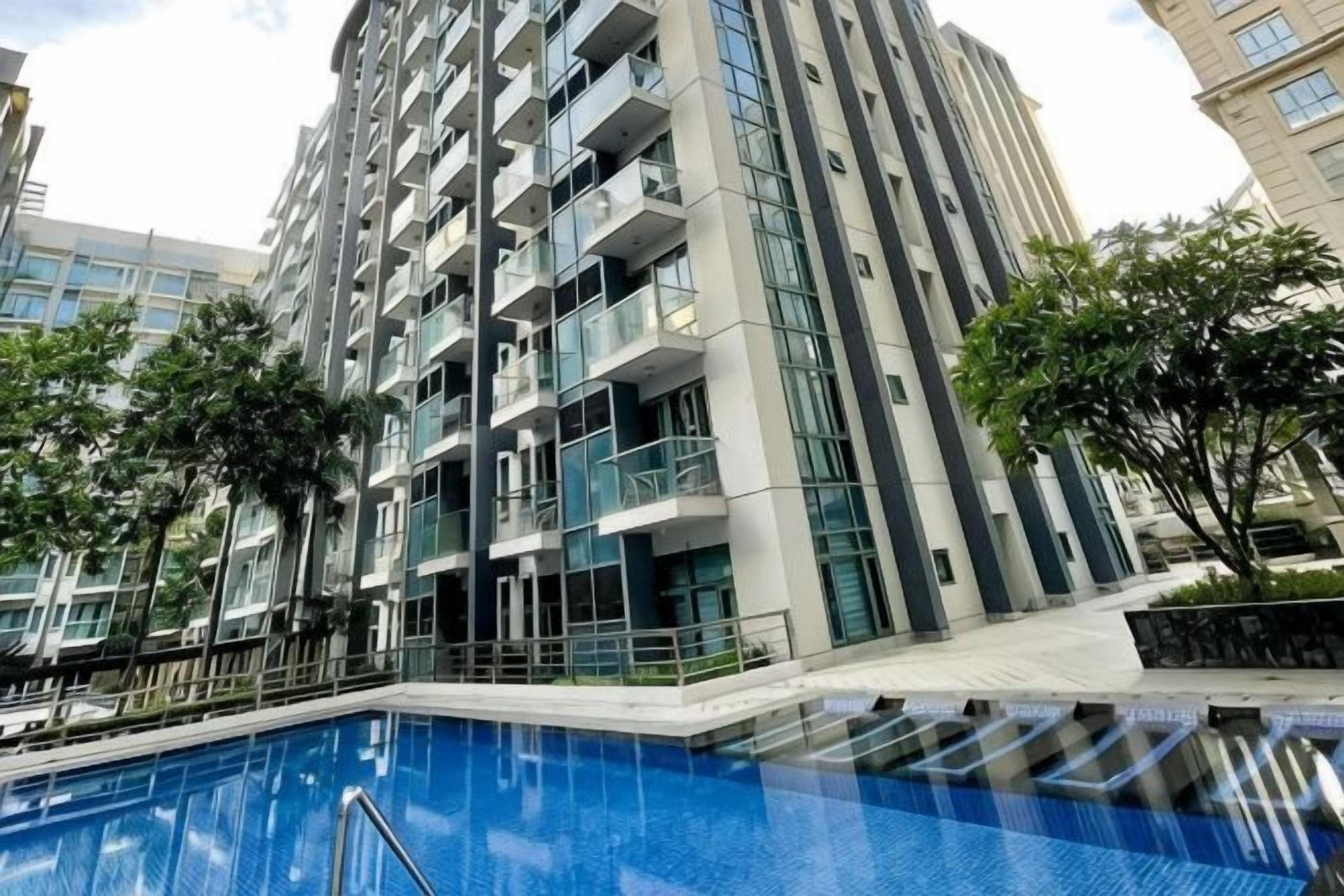 A modern high-rise building with a swimming pool in the foreground.