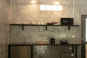 Une cuisine équipée d’un four à micro-ondes, d’une cuisinière et d’étagères au-dessus du plan de travail.