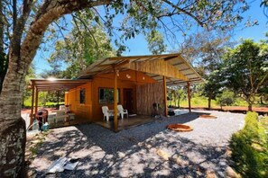 A wooden cabin with a covered patio, outdoor seating, and a gravel ground. - Krabi Kabin (Krabi)