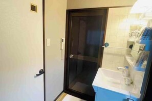 A bathroom with a glass shower door, a white sink, and a blue countertop. - Remembrance (Osaka)