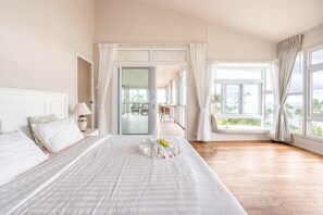 A hotel room with a large bed, a dining area, and a view of the outdoors. - Grand view @lamaibeach (Koh Samui)