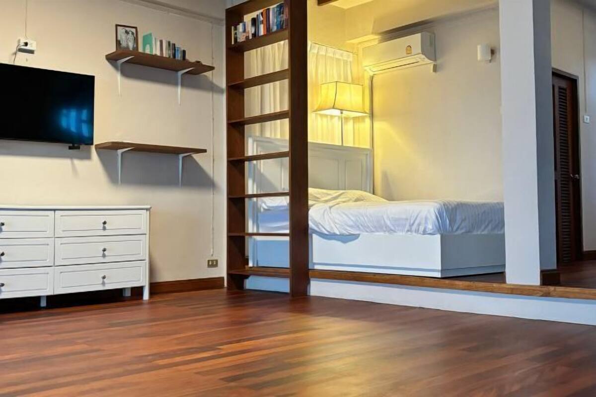 Une chambre à coucher comprenant un lit, un téléviseur, une commode et des étagères intégrées.