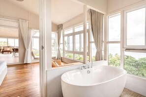 A modern bathroom with a large bathtub, large windows, and a view of the outdoors. - Grand view @lamaibeach (Koh Samui)