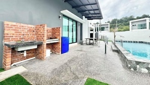 An outdoor patio with a brick barbecue, a pool, and a covered seating area. - Luxury 5BR Home w/ Private Pool, 18Pax, Netflix (Langkawi)