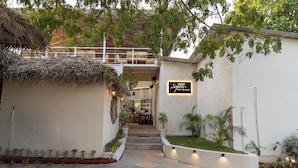 A hotel entrance with a thatched roof, a staircase leading to the bar area, and a sign for "Sofitel". - Destiny Goa Beach Resort (Canacona)