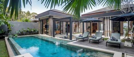 A swimming pool with lounge chairs, a covered seating area, and a modern house in the background.