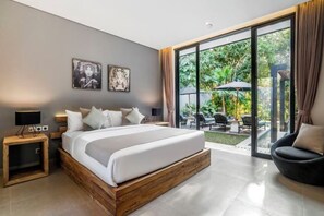 A modern bedroom with a large bed, a nightstand, a chair, and a view of an outdoor patio.