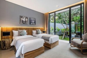 A modern hotel room with two beds, a TV, and a large sliding glass door to a garden.