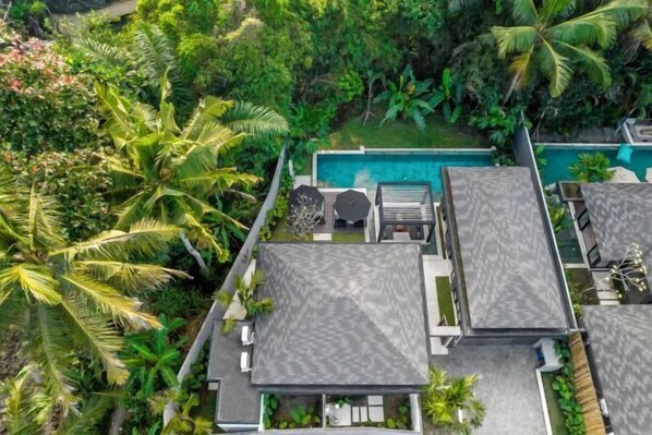 A resort with multiple bungalow-style rooms, a swimming pool, and lush tropical vegetation.