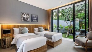 A modern hotel room with two beds, a large sliding glass door to a garden, and a wooden headboard. - Villa Bale Dauh by BaliSuperHost (Bali)
