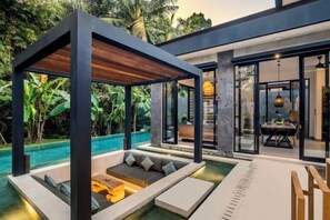 Un espacio exterior moderno con piscina, mobiliario y una estructura cubierta.