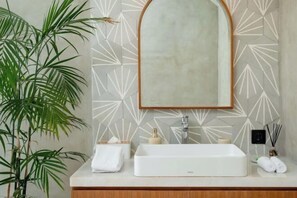 A bathroom with a white sink, a mirror, and a geometric-patterned wall. - Villa Serenya Ubud (Bali)