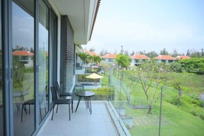 A balcony with a glass door, a small table, and chairs.
