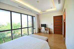Un dormitorio con un ventanal grande, un escritorio y una cama.