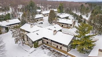 A snow-covered residential area with modern houses, surrounded by trees and hills.