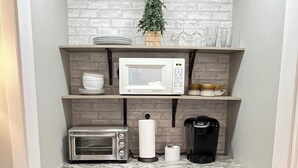 Una kitchenette compacta con microondas, tostadora, cafetera y refrigerador.