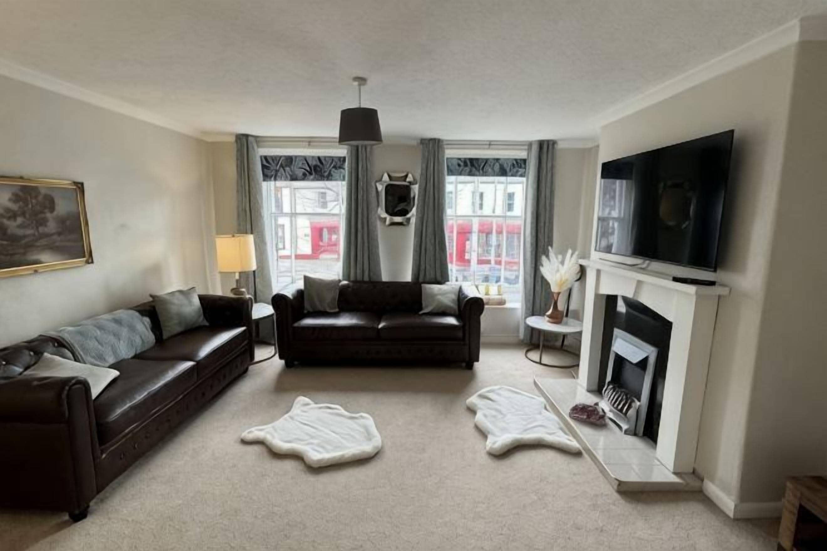 A living room with a sofa, a fireplace, a television, and a window with curtains.