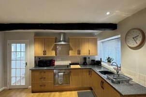 A modern kitchen with wooden cabinets, a stainless steel range hood, and a built-in oven.