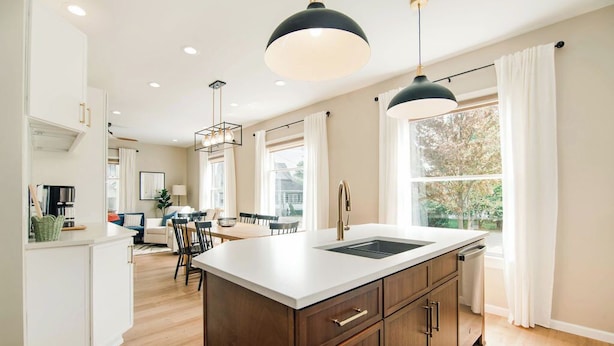 Una cocina moderna con una isla central, armarios de madera e iluminación colgante.