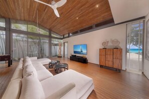 Una sala de estar moderna con un sofá grande, un televisor y un mueble de madera.