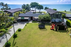 A residential property with a grassy yard, a red slide, and a view of the ocean.