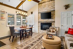 A cozy living room with a fireplace, a dining area, and a sofa.