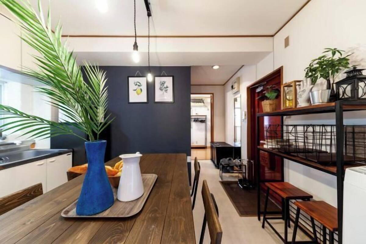 A modern kitchen with a wooden table, a blue vase, and a white pitcher.