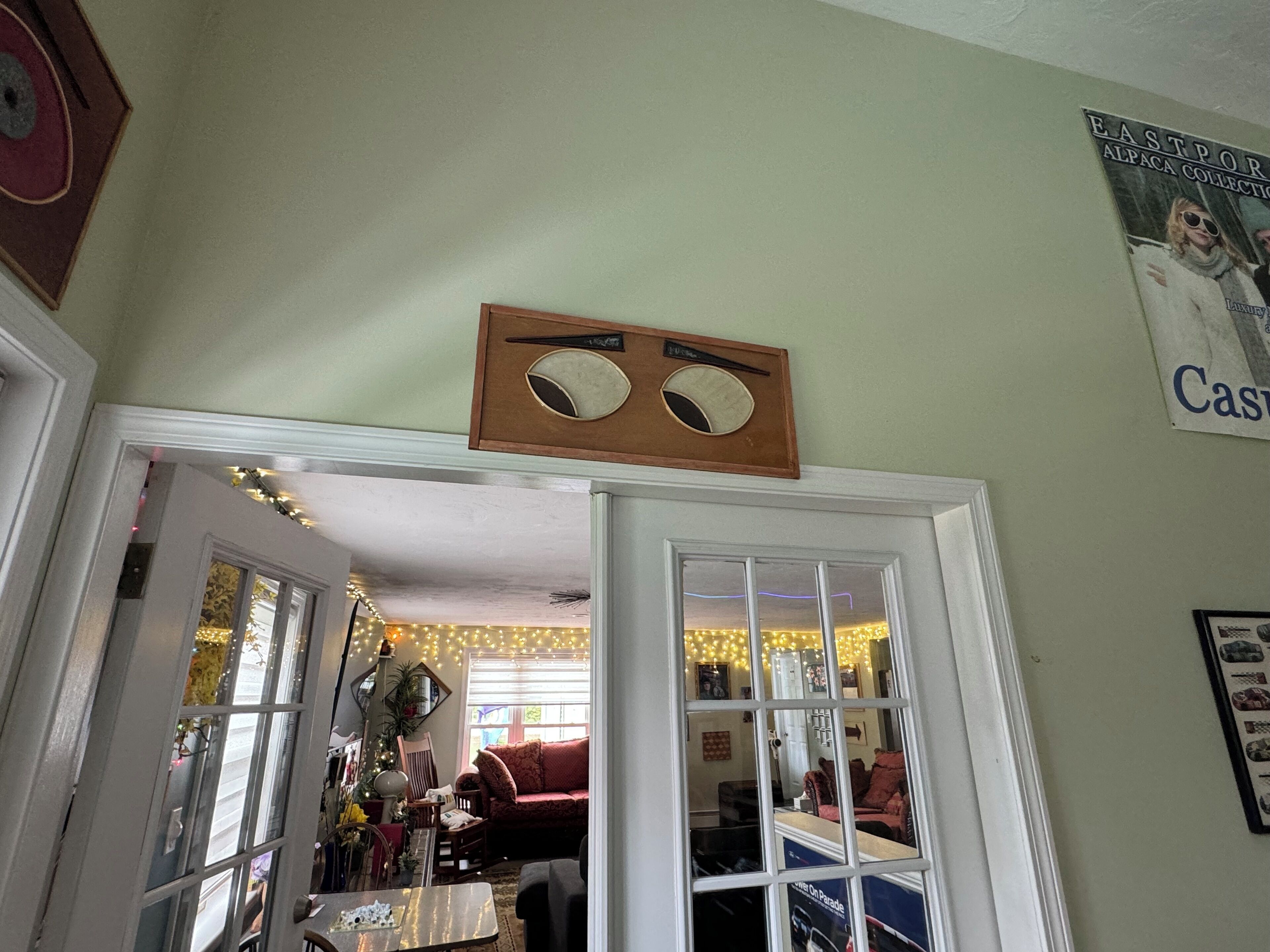 A cozy living room with a wooden headboard, a mirror, and a poster on the wall.